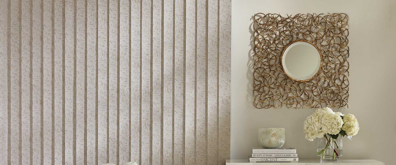 Mirror and hydrangeas next to tan vertical blinds.